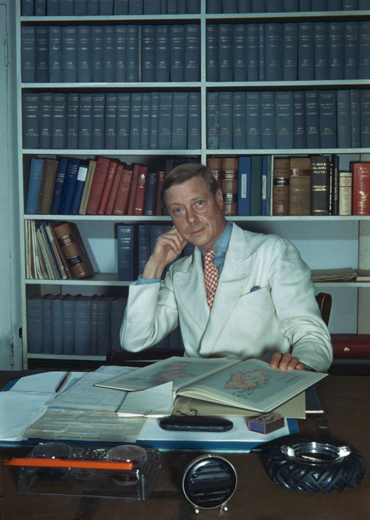 Image Credits: Getty Images / Ivan Dmitri / Michael Ochs Archives | The Duke of Windsor (1894-1972) sitting at a desk, which is strewn with books and paperwork in Goverment House in Nassau, the Bahamas, circa 1942.