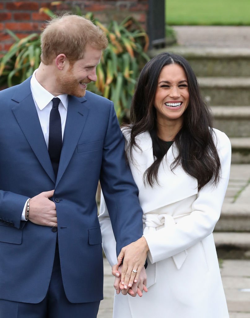 Image Credits: Getty Images / Chris Jackson | Prince Harry and Meghan Markle during an official photocall to announce the engagement of Prince Harry and actress Meghan Markle at The Sunken Gardens at Kensington Palace on November 27, 2017 in London, England. Prince Harry and Meghan Markle have been a couple officially since November 2016 and are due to marry in Spring 2018.