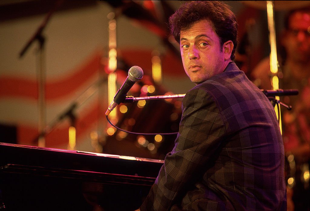Image Credits: Getty Images / Paul Natkin | Musician Billy Joel performs onstage during the first Farm Aid benefit concert at Memorial Stadium, Champaign, Illinois, September 22, 1985. Image Credits: Getty Images / Paul Natkin | Musician Billy Joel performs onstage during the first Farm Aid benefit concert at Memorial Stadium, Champaign, Illinois, September 22, 1985.