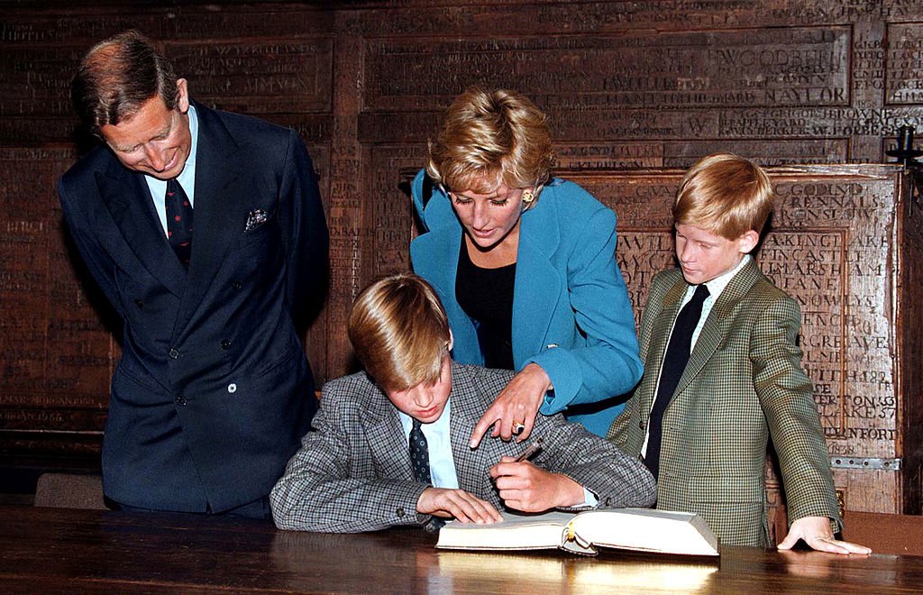 Image Credit: Getty Images / Prince William follows Eton tradition by signing a book before starting at the school, as Prince Charles, Princess Diana (1961 - 1997) and Prince Harry look on, September 1995.