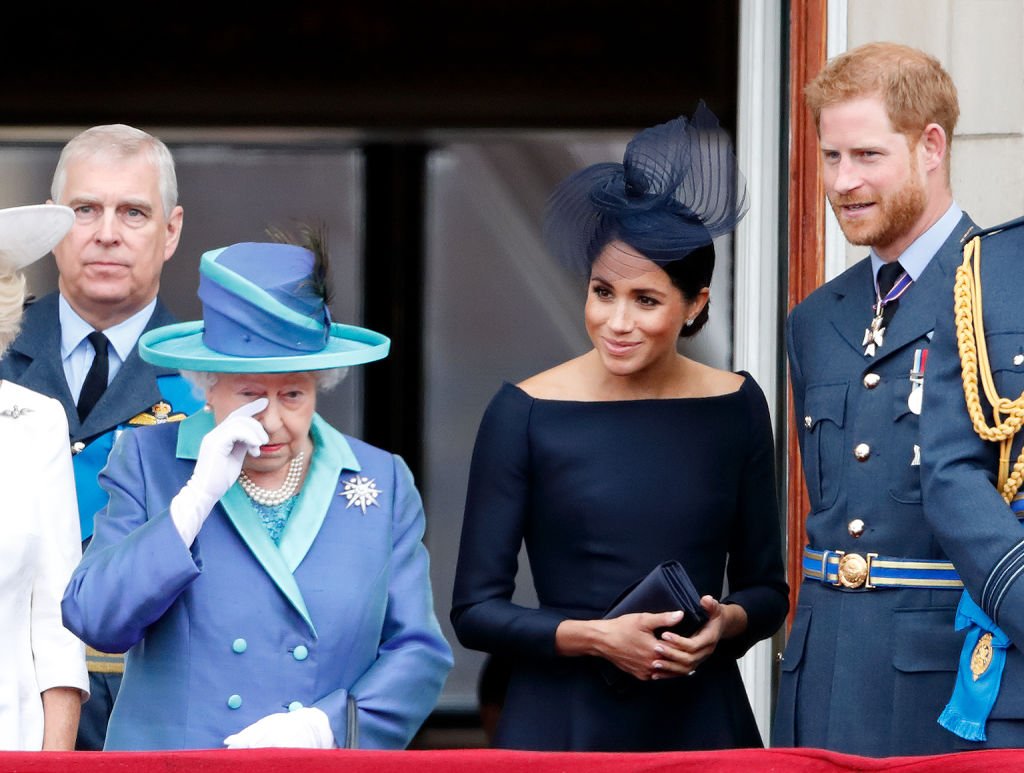 Image Credit: Getty Images / Queen Elizabeth II, Meghan, Duchess of Sussex and Prince Harry, Duke of Sussex watch a flypast to mark the centenary of the Royal Air Force from the balcony of Buckingham Palace on July 10, 2018 in London, England.