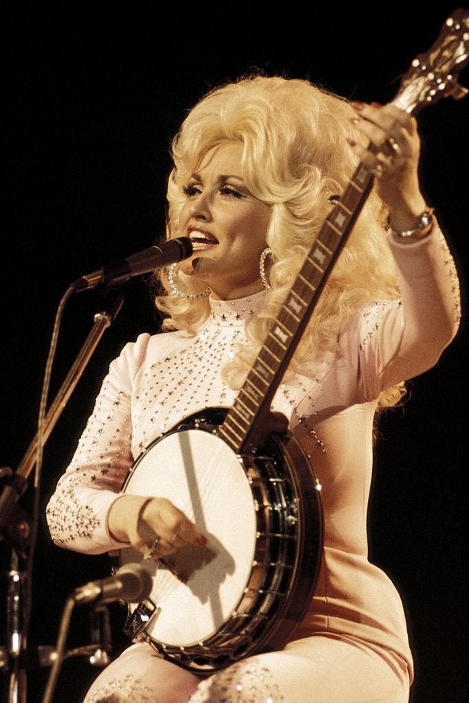 Image Credits: Getty Images / Andrew Putler / Redferns | Photo of Dolly Parton, performing live onstage at the UK Country Music Festival, playing banjo. Image Credits: Getty Images / Andrew Putler / Redferns | Photo of Dolly Parton, performing live onstage at the UK Country Music Festival, playing banjo.