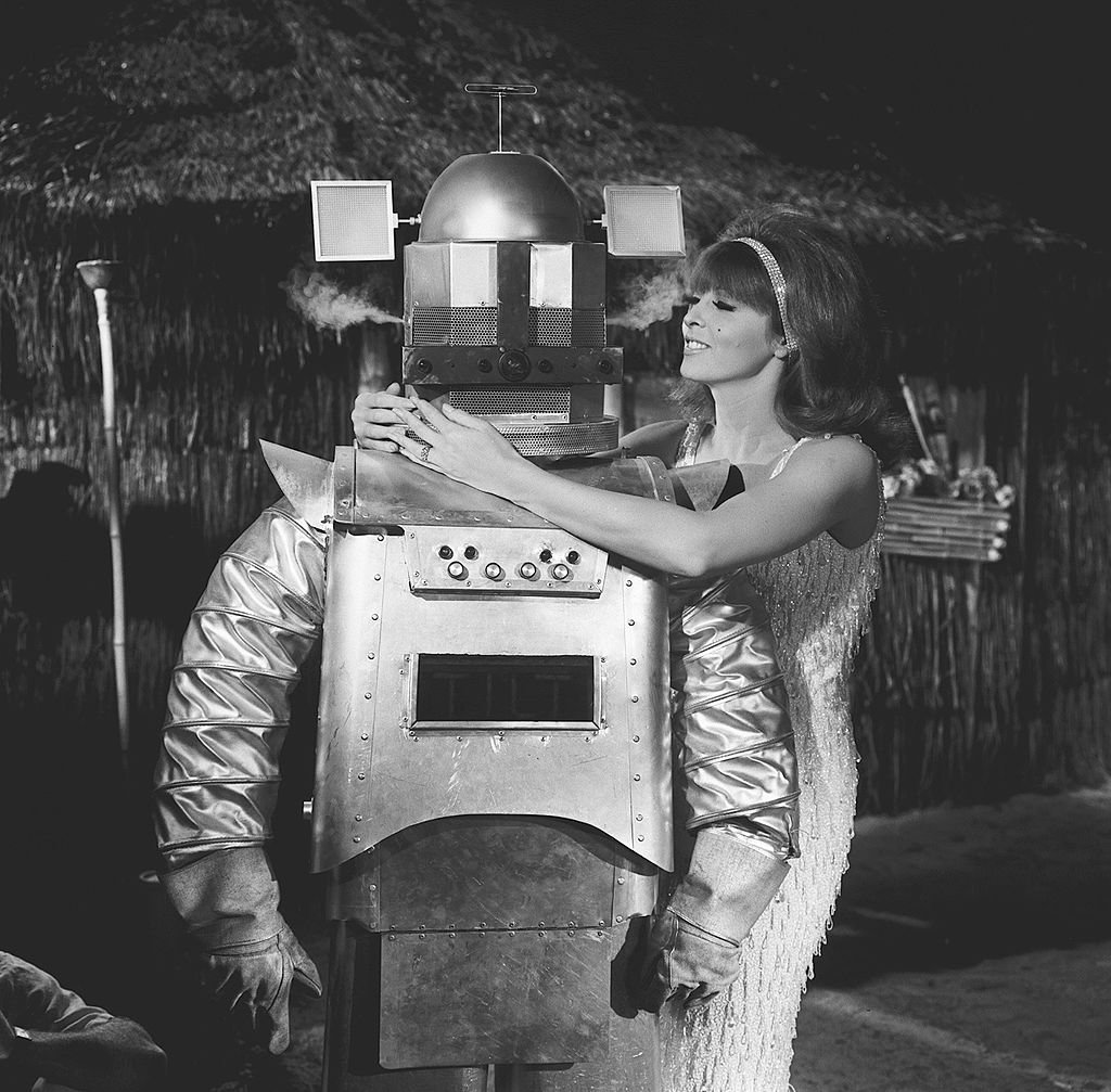 Image Credit: Getty Images / American actress Tina Louise, as Ginger, wraps her arms around the 'shoulders' of a robot (played by Bob D'Arcy) in a scene from an episode of the television comedy 'Gilligan's Island' entitled 'Gilligan's Living Doll,' Los Angeles, California, November 18, 1965.