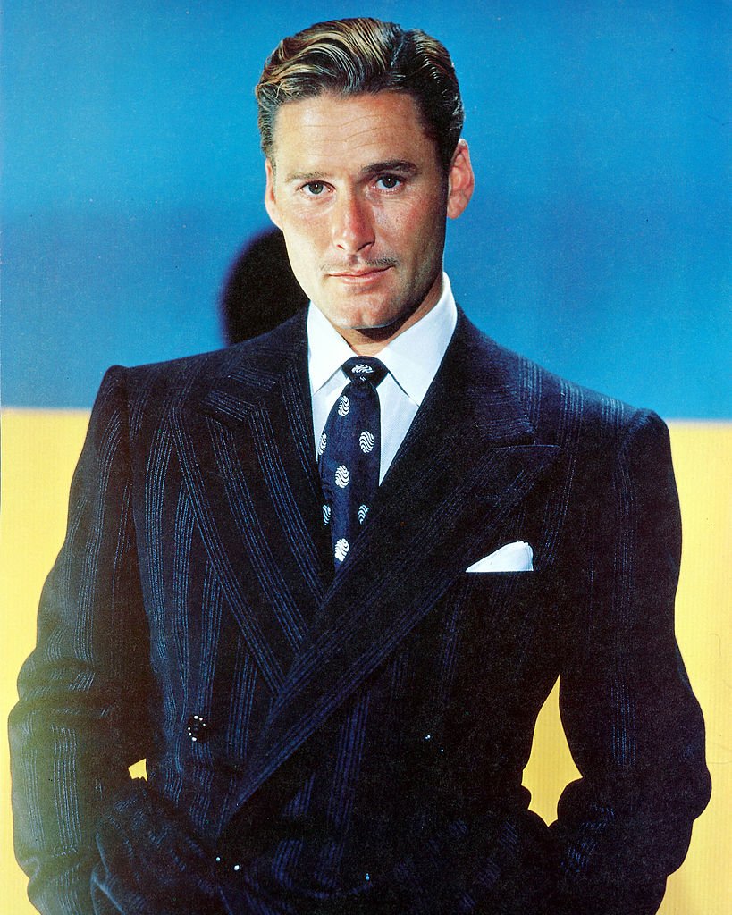 Image Source: Getty Images/Silver Screen Collection/Errol Flynn (1909-1959), Australian actor, wearing a dark blue jacket, white shirt, and blue tie with white motifs in a studio portrait, with a blue background, circa 1945