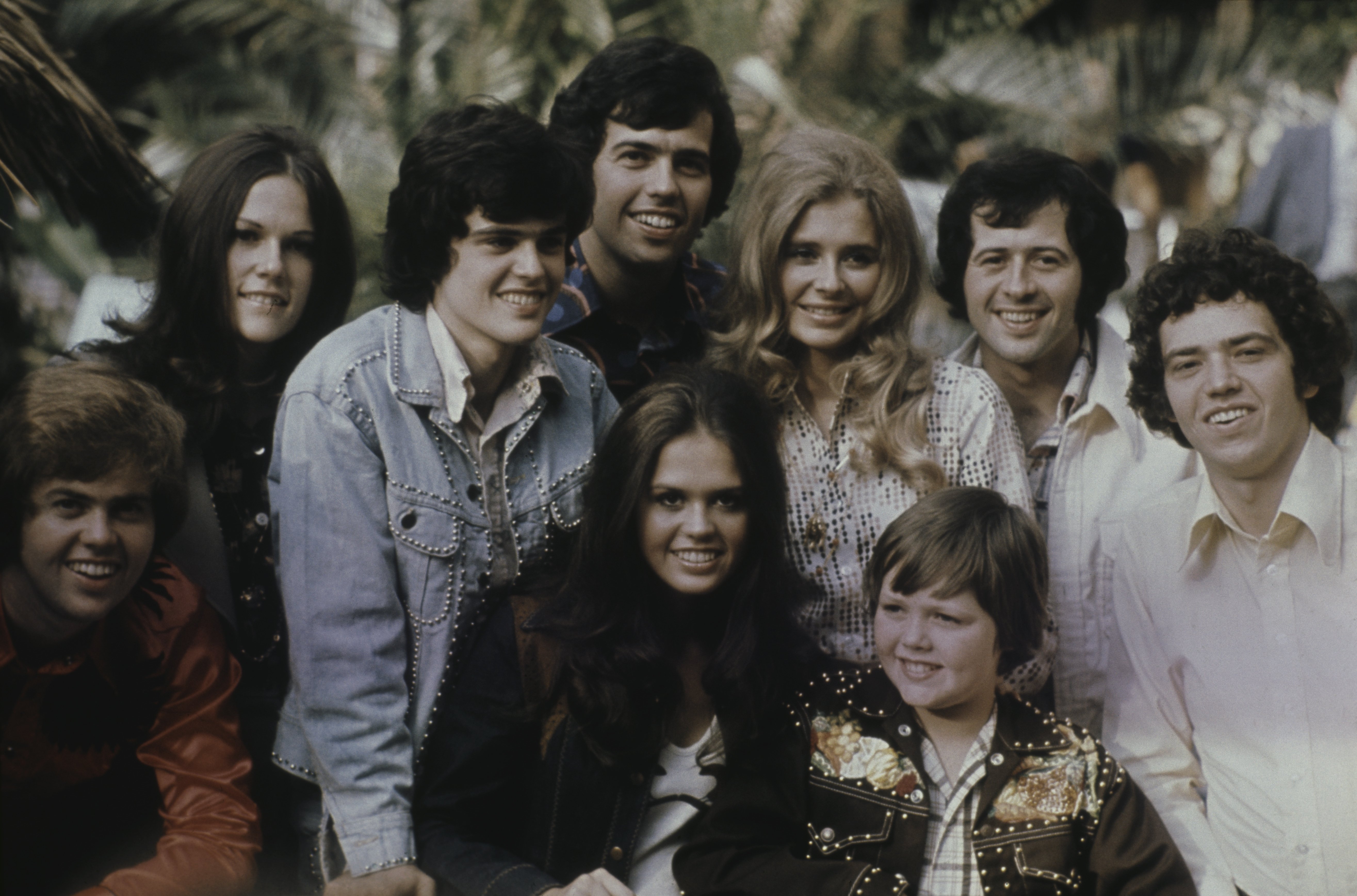 Image Credits: Getty Images / Michael Putland | Group portrait of American family vocal group The Osmonds posed with friends in 1973. Group members are, from left to right, Merrill Osmond, unknown woman, Donny Osmond, Alan Osmond, Marie Osmond, unknown woman, Jimmy Osmond (bottom) Wayne Osmond and unknown man.