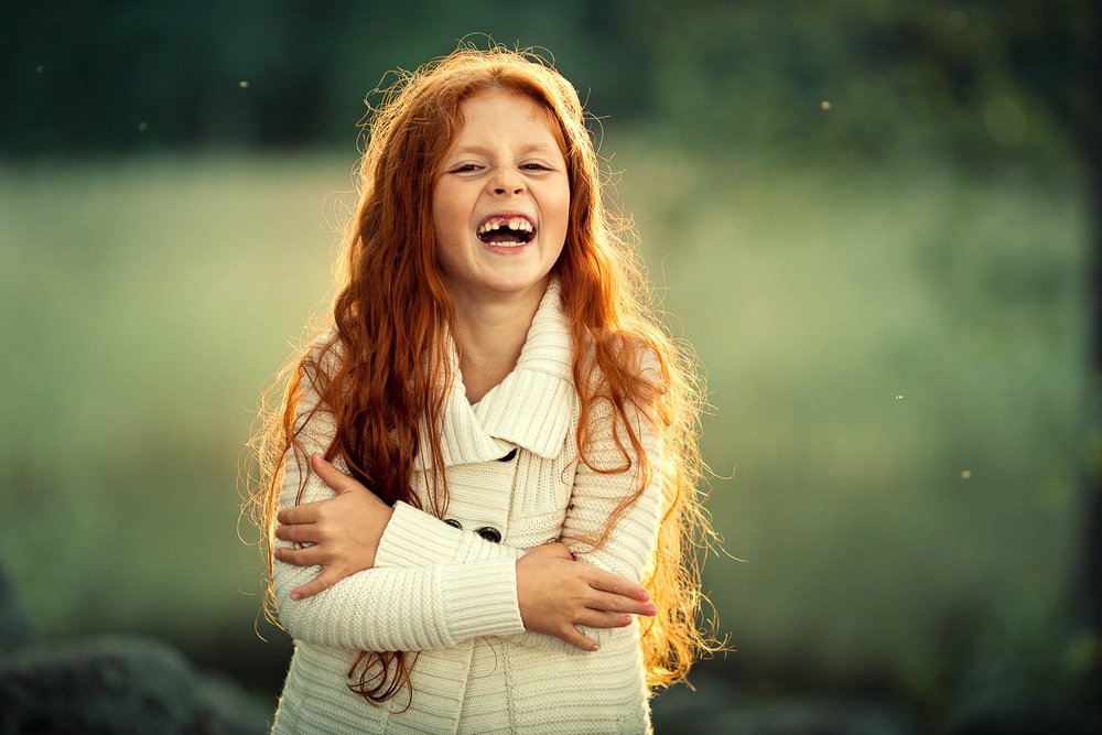 Red haired girl laughing happily | Shutterstock