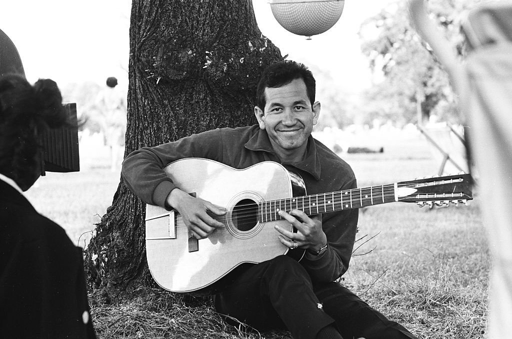 Image Credit: Getty Images / Trini Lopez is filmed sitting playing guitar in a London park, circa 1965.