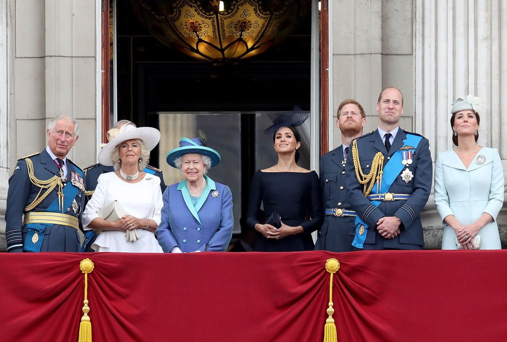 Image Credits: Getty Images / Chris Jackson | (L-R) Prince Charles, Prince of Wales, Camilla, Duchess of Cornwall, Queen Elizabeth II, Meghan, Duchess of Sussex, Prince Harry, Duke of Sussex, Prince William, Duke of Cambridge and Catherine, Duchess of Cambridge watch the RAF flypast on the balcony of Buckingham Palace, as members of the Royal Family attend events to mark the centenary of the RAF on July 10, 2018 in London, England.