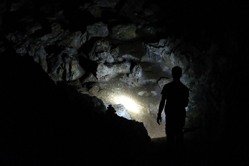 Silhouette of a man exploring a cave with a torch | Shutterstock
