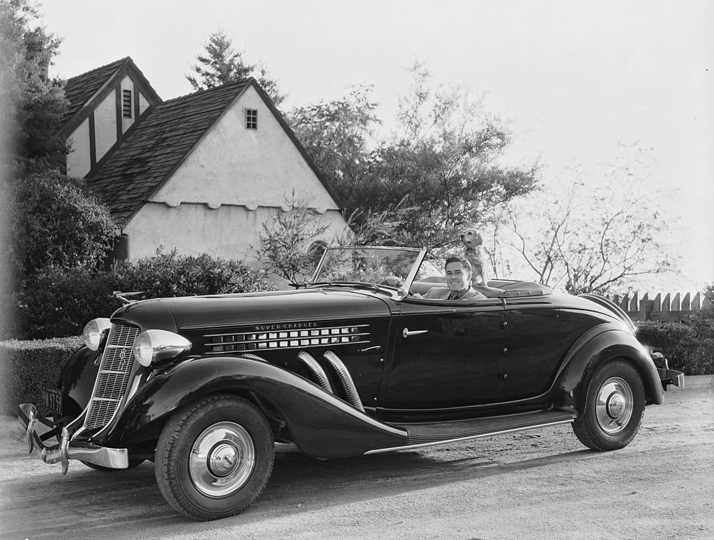 Image Source: Getty Images / Actor Errol Flynn (1909-1959), known as the king of swashbuckler films, goes for a drive in his convertible with his dog.