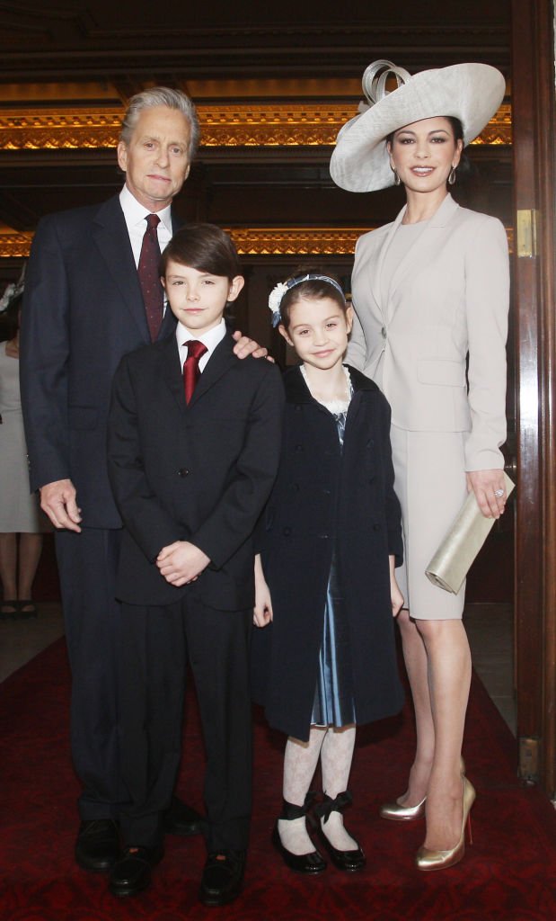 Image Credits: Getty Images / Lewis Whyld - WPA Pool | Actress Catherine Zeta Jones (R) arrives with her husband, actor Michael Douglas and their children Dylan and Carys Douglas, to attend a Royal Investiture at Buckingham Palace on February 24, 2011 in London, England.