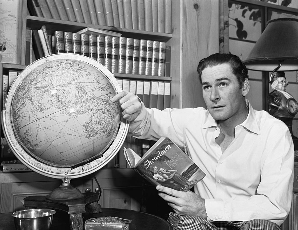 Image Source: Getty Images / Screen actor and adventurer Errol Flynn eyes the globe as he plans South Seas voyage in his Schooner.