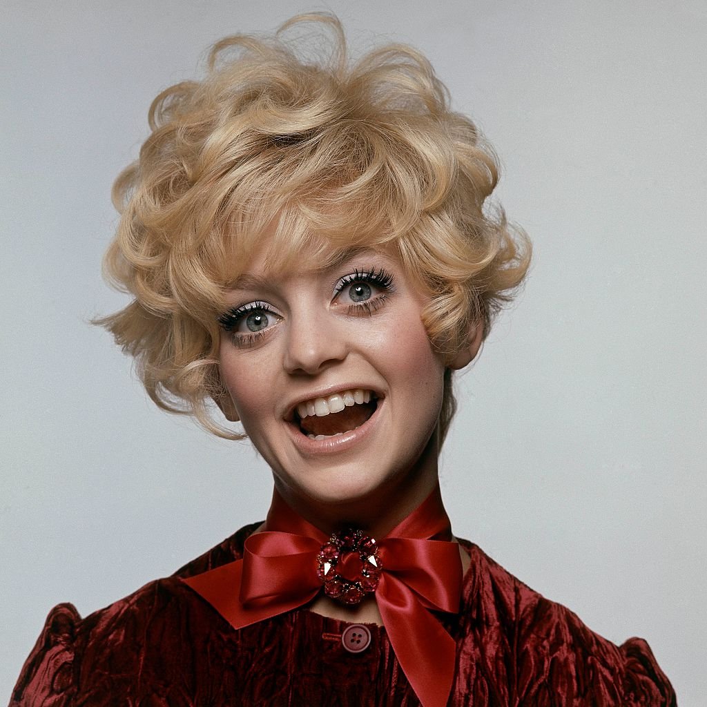 Image Credits: Getty Images / Bert Stern / Condé Nast | Model and actress Goldie Hawn in a burgundy velvet dress by Weber Originals, a satin ribbon tied in a bow at neck with a pin by Bergere.