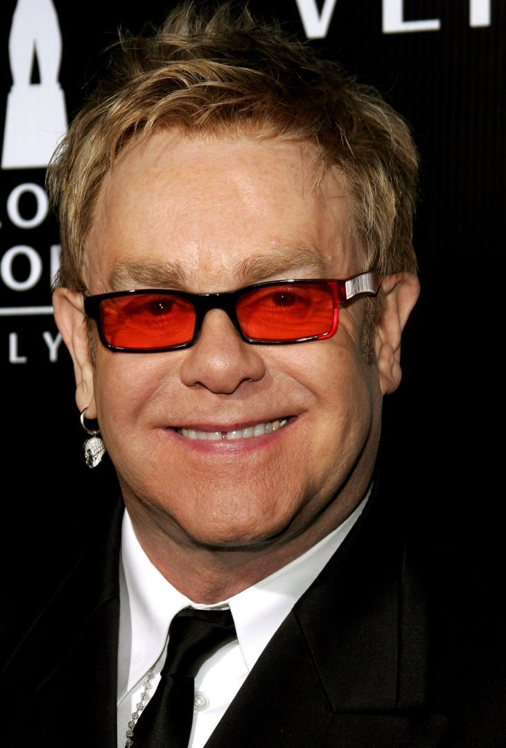 Image Credits: Getty Images / Elton John poses on the red carpet.