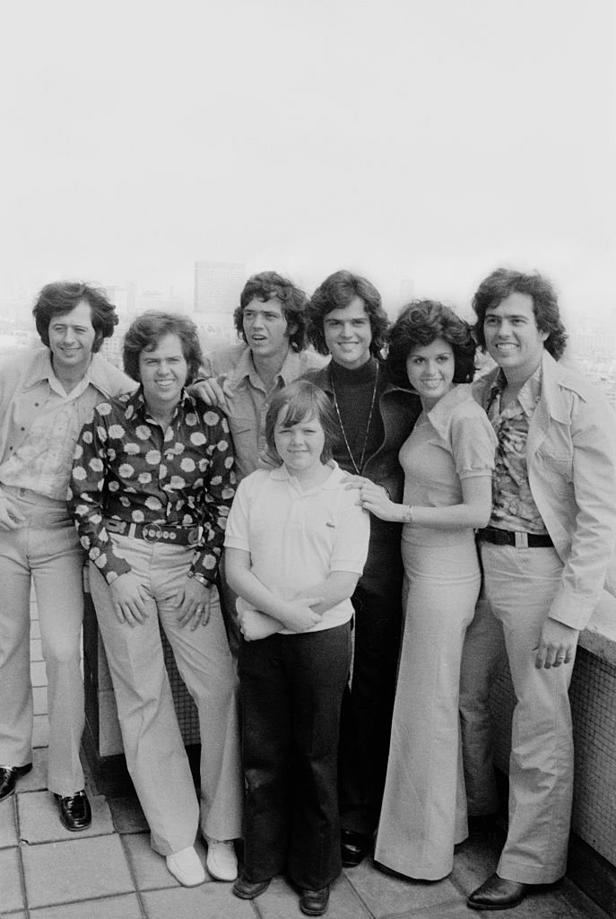 Image Credits: Getty Images / Michael Putland | Wayne Osmond, Merrill Osmond, Jay Osmond, Jimmy Osmond, Donny Osmond, Marie Osmond and Alan Osmond.