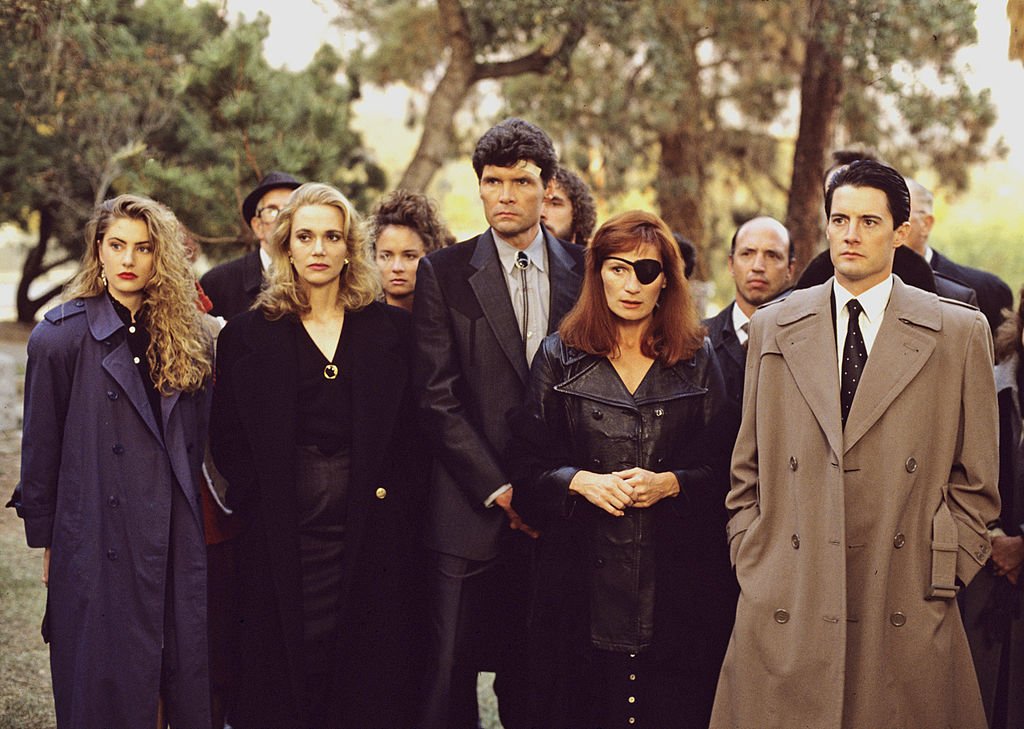 Image Credits: Getty Images / Walt Disney Television | Twin Peaks, Episode Three, Season One. FBI Special Agent Dale Cooper (Kyle MacLaughlin, right) at former homecoming queen Laura Palmer's funeral with a lineup of mourners/suspects, from left: Shelly Johnson (Madchen Amick), Norma Jennings (Peggy Lipton), Ed Hurley (Everett McGill) and Nadine Hurley (Wendy Robie).