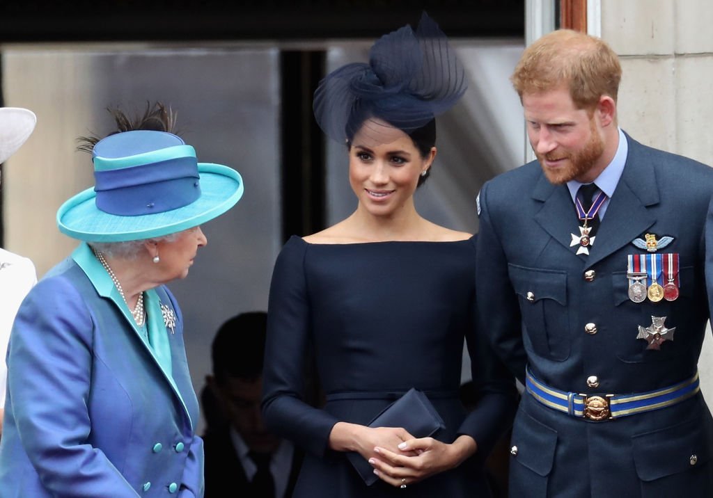 Image Credits: Getty Images / Chris Jackson | Queen Elizabeth II, Meghan, Duchess of Sussex, Prince Harry, Duke of Sussex watch the RAF flypast on the balcony of Buckingham Palace, as members of the Royal Family attend events to mark the centenary of the RAF on July 10, 2018 in London, England.