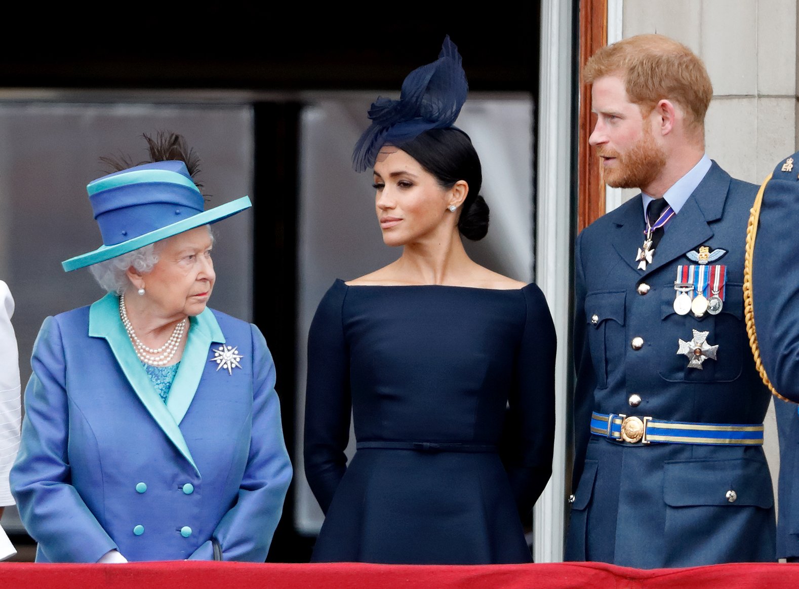 Image Credit: Getty Images / Queen Elizabeth II, Meghan, Duchess of Sussex and Prince Harry, Duke of Sussex watch a flypast to mark the centenary of the Royal Air Force from the balcony of Buckingham Palace on July 10, 2018 in London, England.