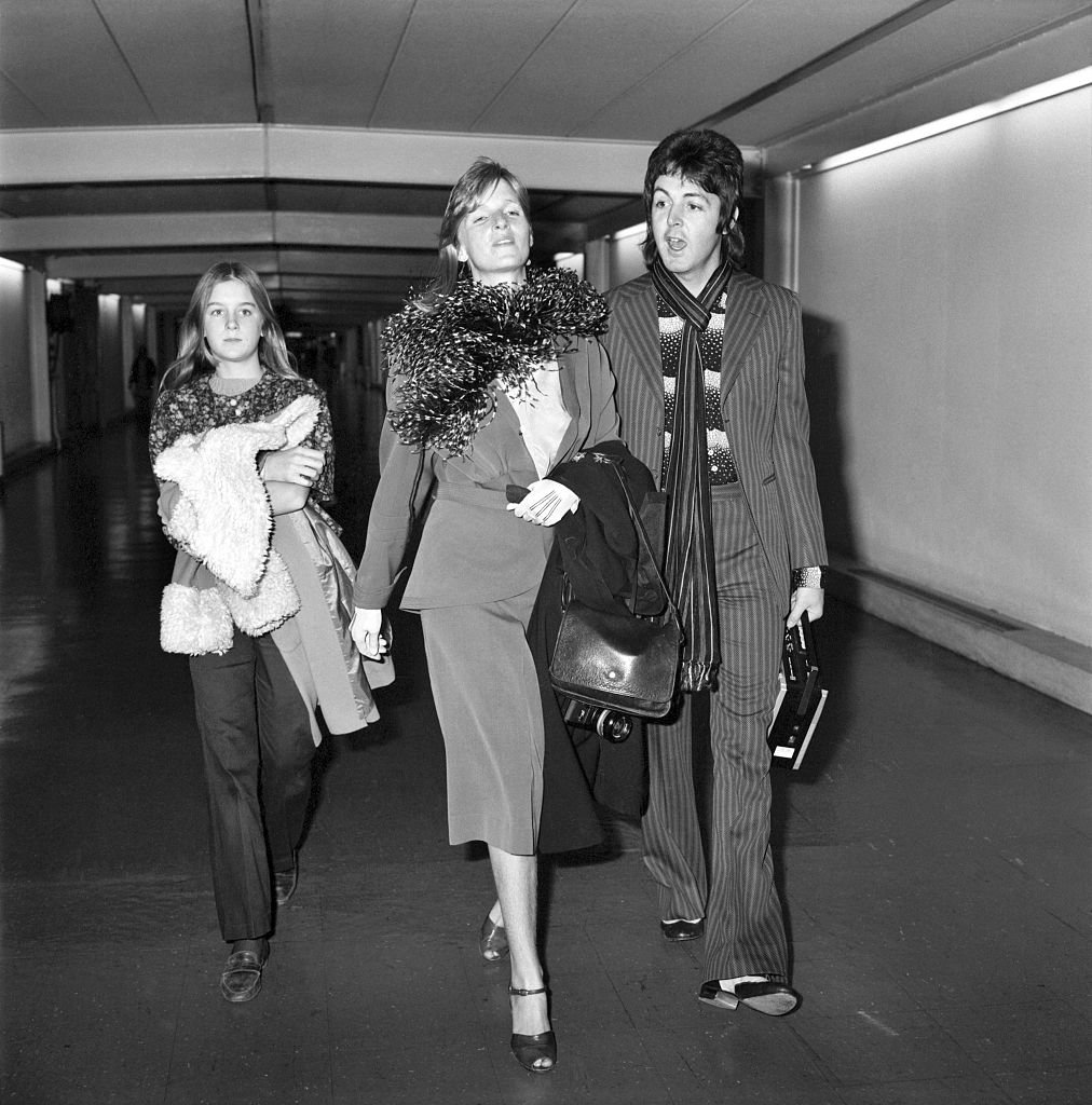 Image Credits: Getty Images / WATFORD / Mirrorpix | Carrying a portable radio, ex-Beatle Paul McCartney leaves Heathrow Airport today for a New York business trip, accompanied by his wife Linda, her daughter Heather.
