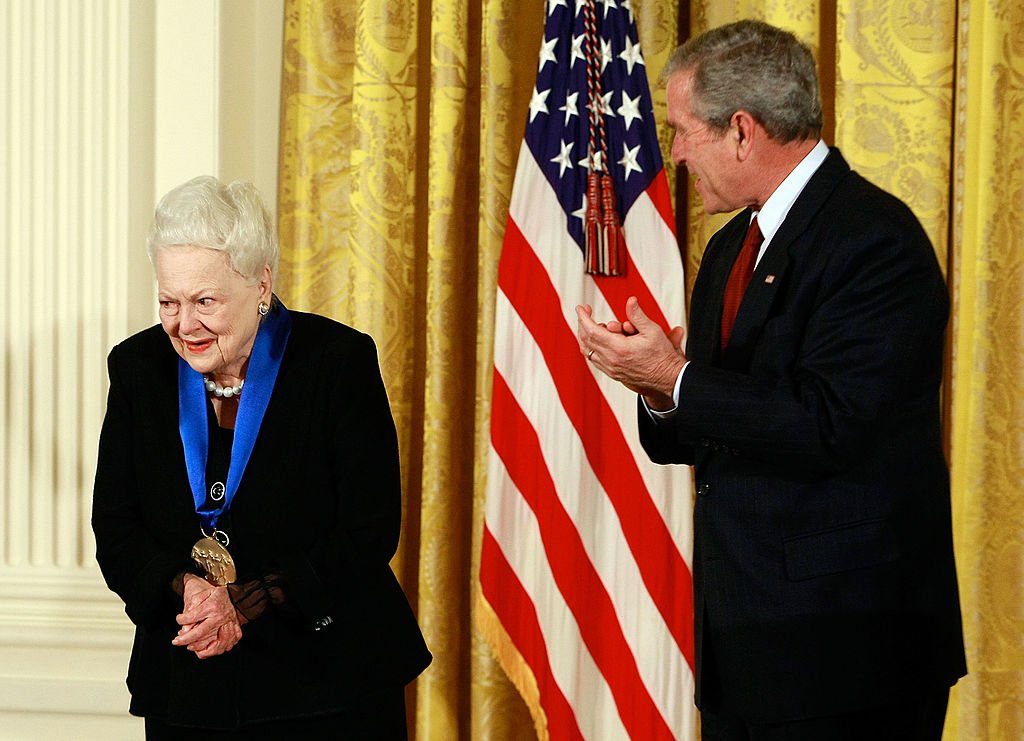 Image Credits: Getty Images / Mark Wilson | U.S. President George W. Bush congratulates actress Olivia de Havilland after presenting her with the 2008 National Medals of Arts award Image Credits: Getty Images / Mark Wilson | U.S. President George W. Bush congratulates actress Olivia de Havilland after presenting her with the 2008 National Medals of Arts award