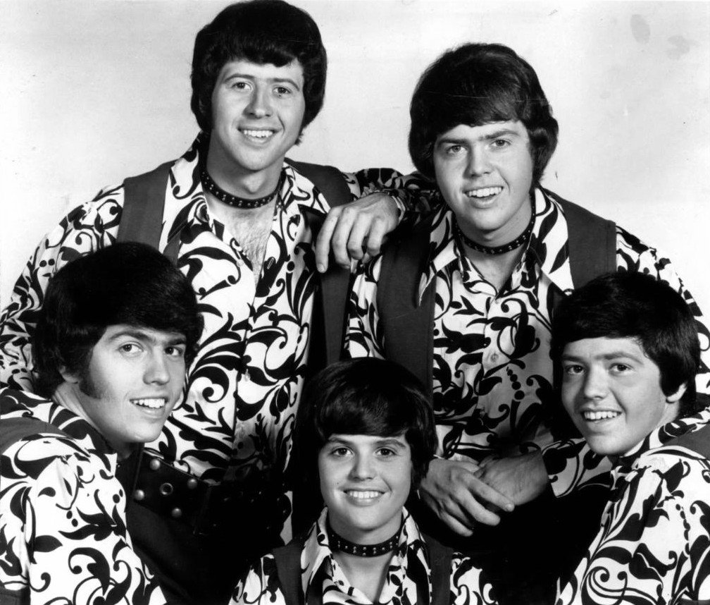 Image Source: Wikimedia Commons/Public Domain/ The Osmonds in 1971 (Clockwise from lower left: Alan, Wayne, Merrill, Jay, Donny)