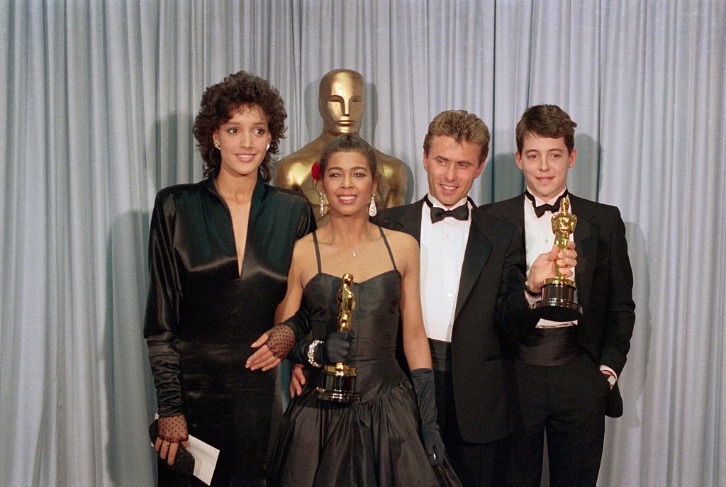 Image Credits: Getty Images / Bettmann | Irene Cara with actress Jennifer Beals, songwriter Keith Forsey, and actor Mathew Broderick.