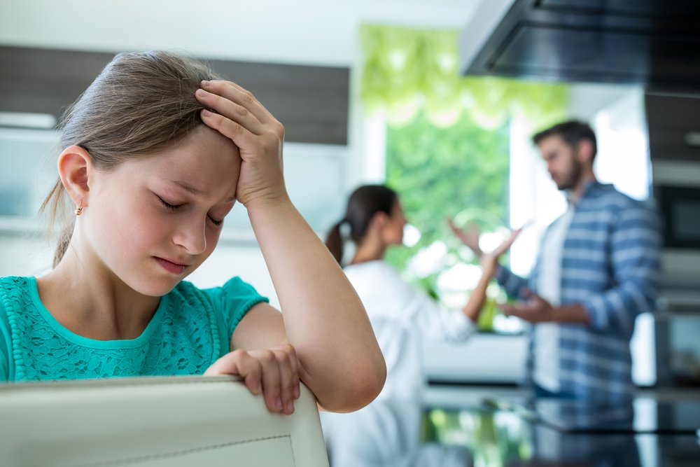 Parents fight behind child | Shutterstock Parents fight behind child | Shutterstock