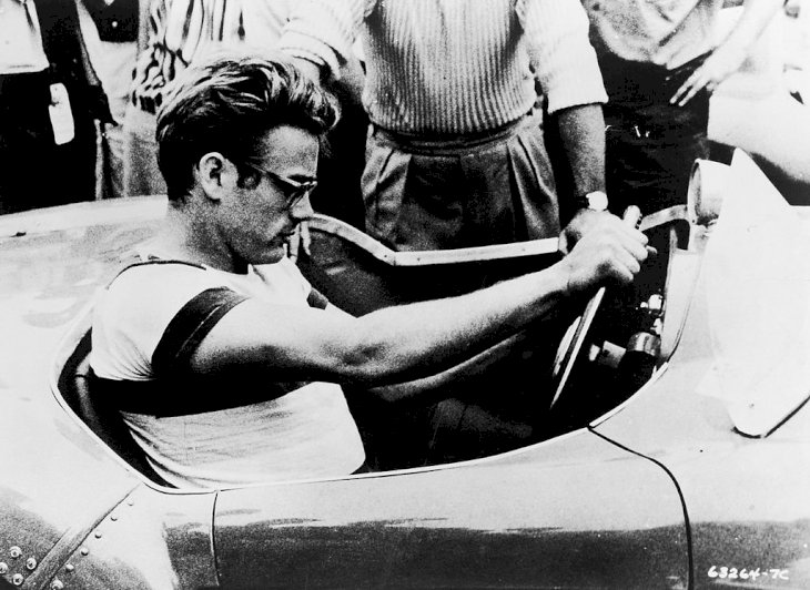 Image Credit: Getty Images/Warner Bros. courtesy of Getty Images | James Dean sits behind the wheel of a sportscar