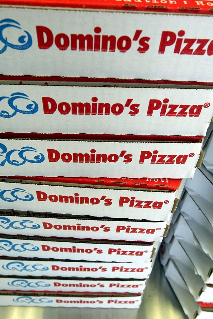 Image Credits: Getty Images / Joe Raedle | Stack of Domino's Pizza boxes.