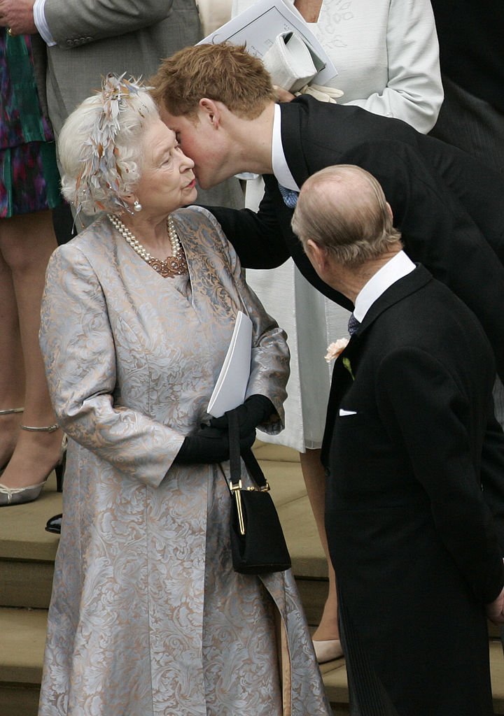 Image Credits: Getty Images / POOL / Tim Graham Picture Library | Prince Harry kisses his grandmother Queen Elizabeth II after the wedding of Peter Phillips to Autumn Kelly, at St George's Chapel in Windsor Castle on May 17, 2008 in Windsor, England.