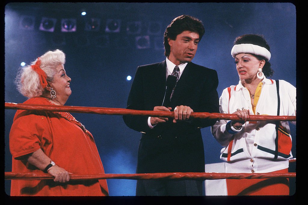 Image Credits: Getty Images / Laura Luongo / Liaison | "Late Show" host Ross Shaffer speaks with Jacqueline Stallone in the ring May 4, 1988 in Los Angeles, CA. Jacqueline Stallone manages the all-female wrestling team GLOW Girls (Gorgeous Ladies Of Wrestling) which has achieved fame through their use of colorful costumes and elegant acrobatics.
