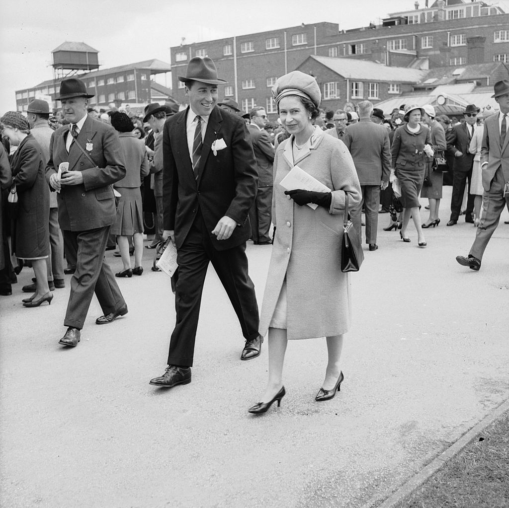 Image Credits: Getty Images / Roger Jackson / Central Press | Queen Elizabeth II and Lord Porchester at Newbury Races. Lord Porchester took over from Michael Oswald as the Queen's racing manager in 1970.