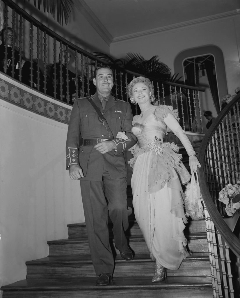 Image Source: Getty Images/Fred MorleyEnglish actress Anna Neagle (1904 - 1986) and actor Errol Flynn (1909 - 1959) enter a reproduction of Romano's Restaurant on the Strand at the ABC studios in Elstree, UK, during the filming of 'Lilacs in the Spring', 3rd June 1954