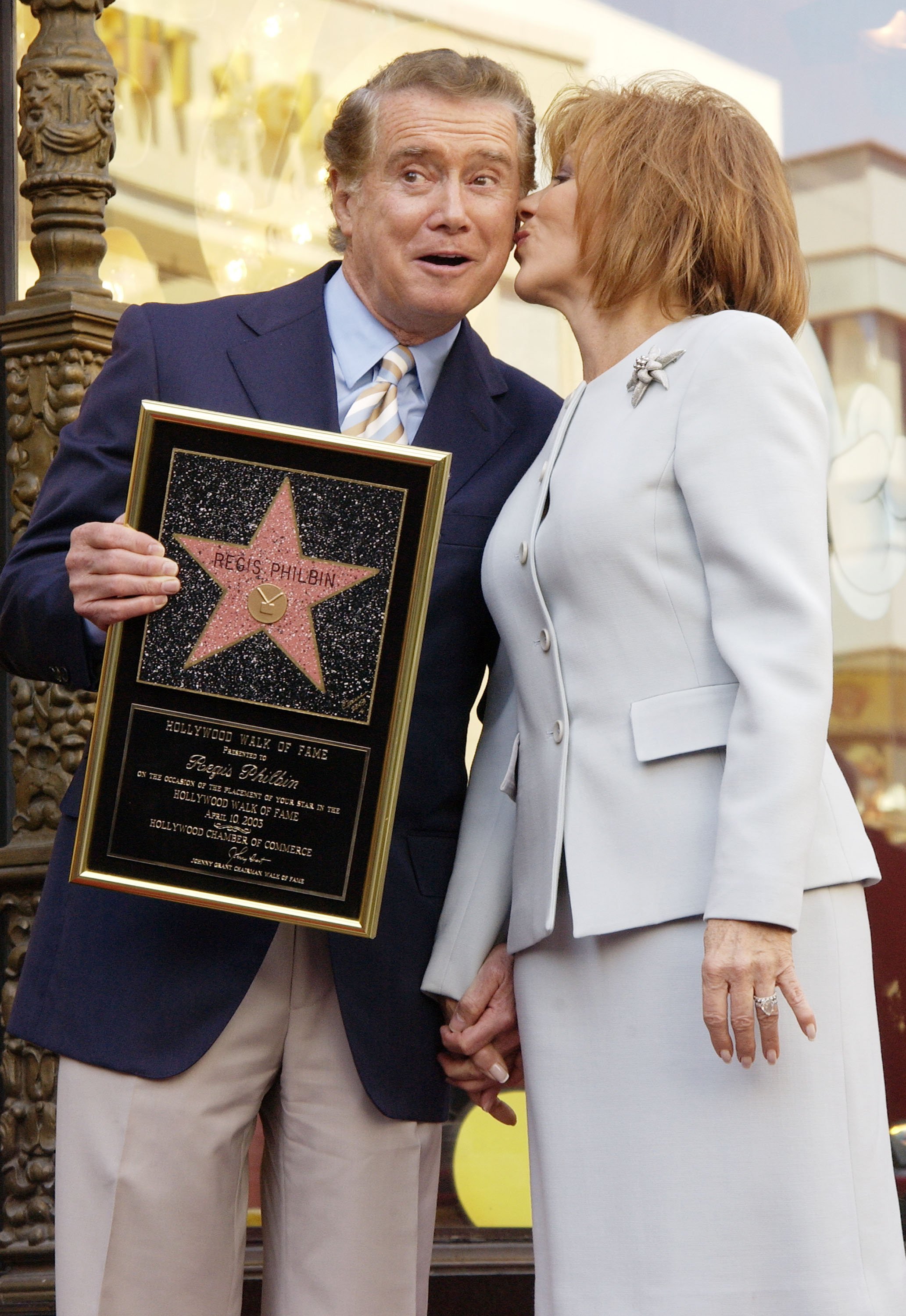 Image Credits: Getty Images | Regis Philbin receiving a smooch from his wife