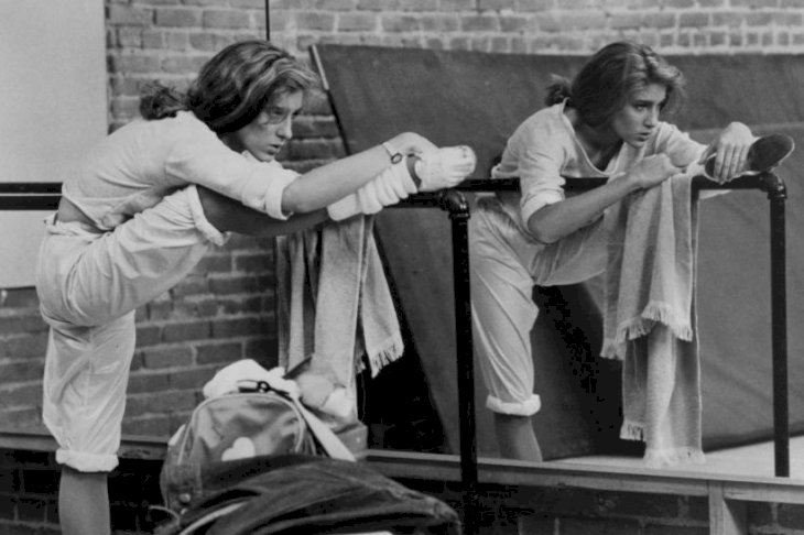 Image Credits: Getty Images / New World Pictures | Sarah Jessica Parker limbers up with unidentified actor prior to her rehearsing her dance steps for the DTV finals in a scene from the film 'Girls Just Want To Have Fun', 1985. Image Credits: Getty Images / New World Pictures | Sarah Jessica Parker limbers up with unidentified actor prior to her rehearsing her dance steps for the DTV finals in a scene from the film 'Girls Just Want To Have Fun', 1985.